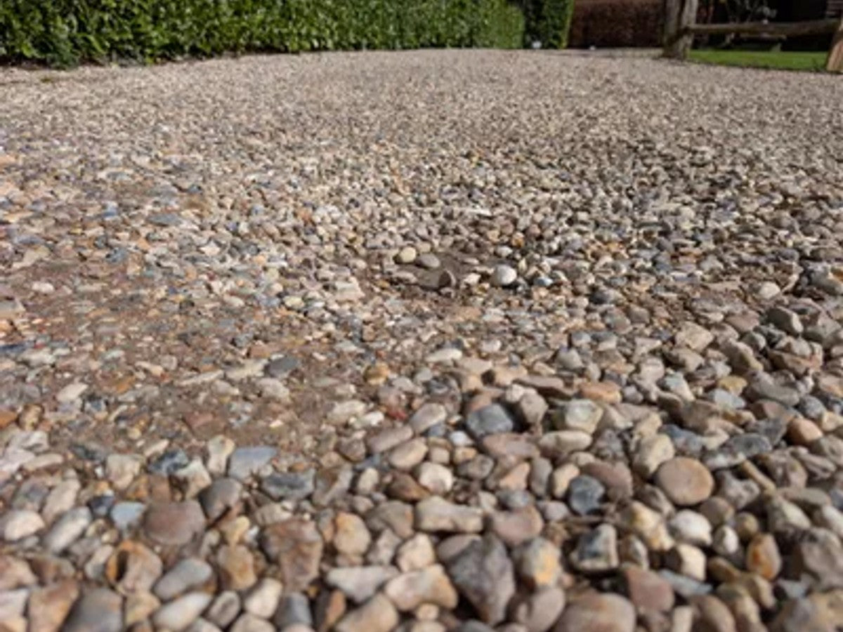 Permeable gravel driveway with stabilisation grids and aluminium edging, showing effective drainage after rain