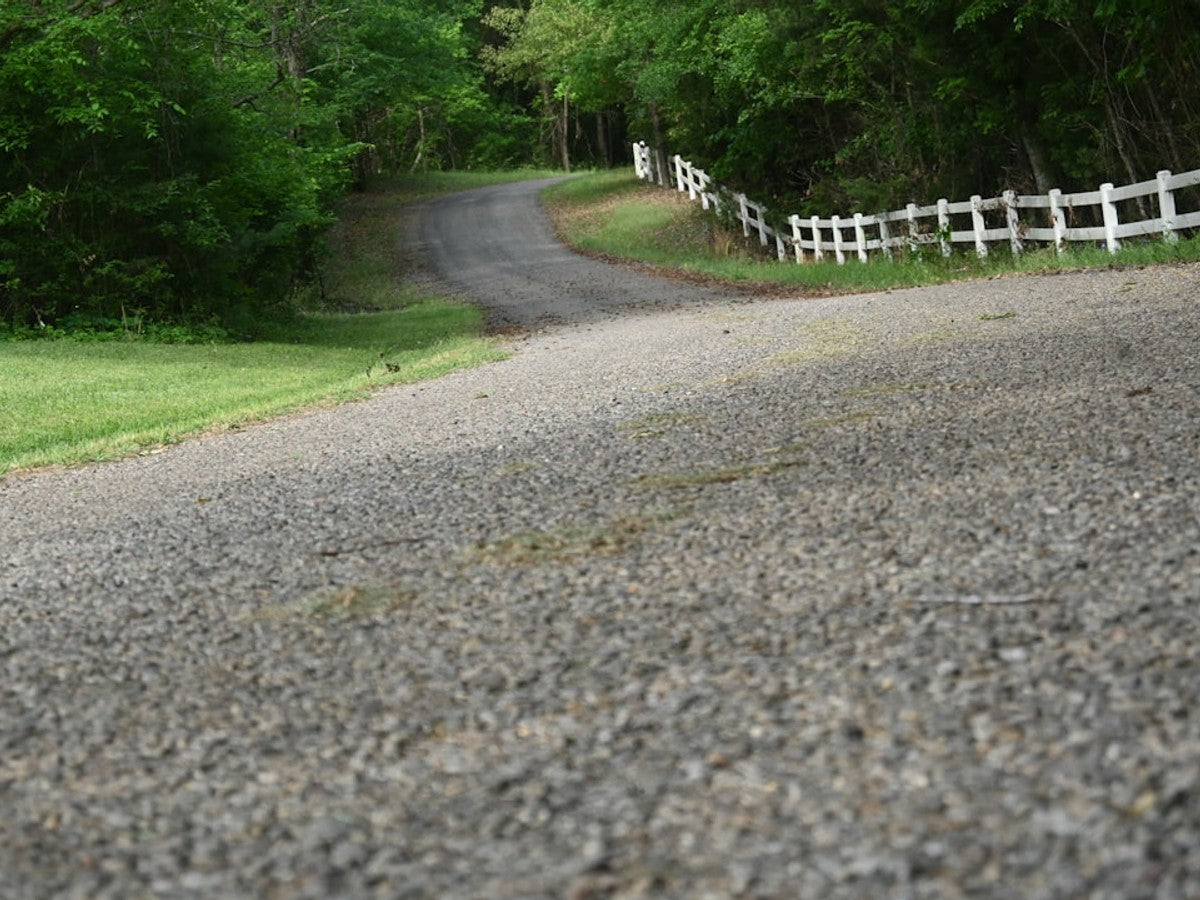 Measuring driveway gradient with a spirit level and timber board to check gravel grid suitability